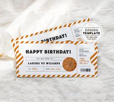 two basketball ticket cards sitting on top of a white sheet with orange and black stripes