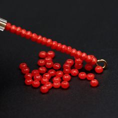 a red beaded keychain on a black surface with some beads attached to it