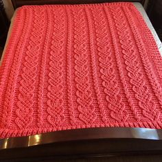 a bed with a red blanket on top of it next to a wooden headboard