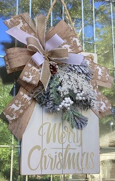 a christmas sign hanging from the side of a building with a bow on it's front door