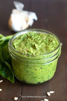 a jar filled with green pesto next to garlic