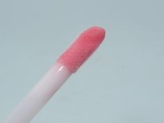 a close up of a pink and white lip brush