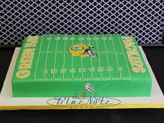 a football field cake with green and yellow frosting on the top, sitting on a black table