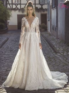 a woman in a wedding dress standing on a cobblestone street