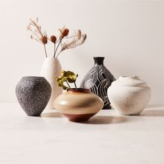 four different vases are lined up on the counter top, one is black and white