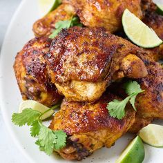 grilled chicken with limes and herbs on a white platter, ready to be served