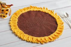 a crocheted sunflower placemat next to a fork and knife