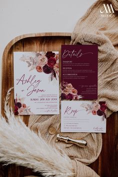 the wedding stationery is laid out on a wooden tray with furs and flowers