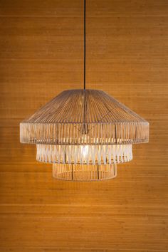 a chandelier hanging from the ceiling in front of a bamboo wall with wood paneling