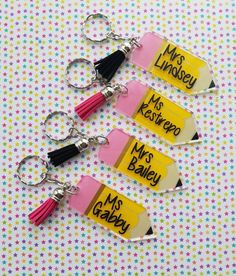 three personalized key chains with tassels are shown on a polka dot background