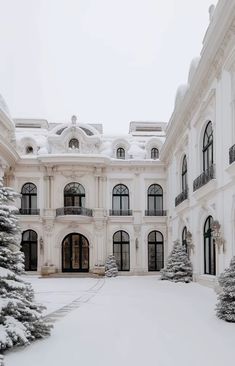 a large white building with snow on the ground and trees in front of it,