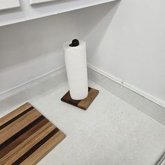 a roll of toilet paper sitting on top of a wooden floor next to a rug