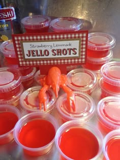 several plastic cups with red jello shots in them and a sign that says, strawberry lemonade jello shots