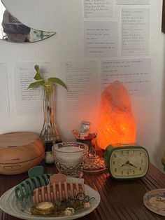 a table topped with lots of different items on top of a wooden table next to a clock