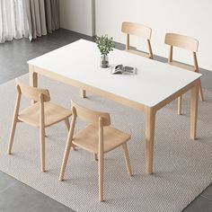 a white table with four wooden chairs and a book on the floor next to it