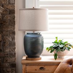 a blue vase sitting on top of a wooden table next to a lamp and chair