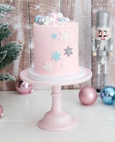 a pink frosted cake sitting on top of a table next to ornaments and a nutcracker