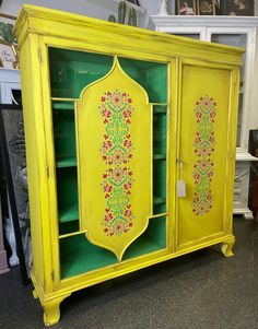 a yellow cabinet with floral designs painted on it