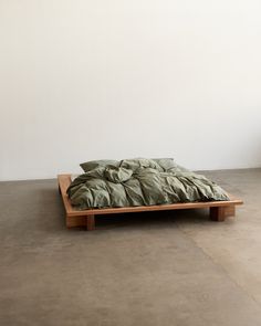 an unmade bed sitting on top of a wooden platform next to a white wall