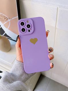 a person holding up a purple phone case with a heart on it and two fingers