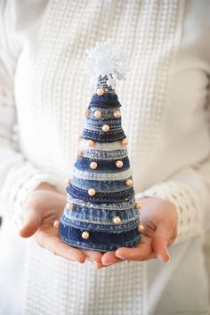 a person holding a small christmas tree made out of denims and buttons on their hands