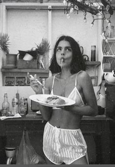 a woman standing in a kitchen holding a plate