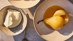 two plates with desserts on them and spoons next to one plate that has fruit in it