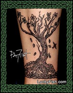 a tree tattoo on the leg with birds flying around it