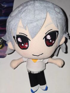 a stuffed doll with grey hair and red eyes sitting on top of a white table