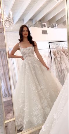 a woman standing in front of a mirror wearing a wedding dress