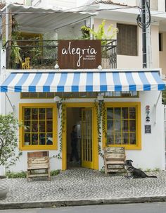 a yellow and blue striped awning on the outside of a building with two wooden benches in front of it