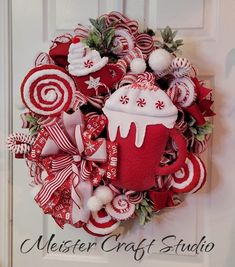 a red and white christmas wreath with candy canes, hot chocolate cup and candies