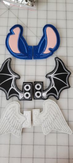 two cookie cutters with wings on them sitting on a tiled floor next to scissors