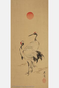 two cranes standing next to each other in front of a red sun