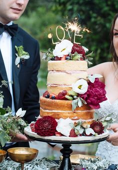 a man and woman standing next to each other in front of a cake