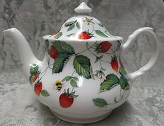 a white tea pot with strawberries on it