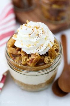 a dessert in a glass jar with whipped cream on top and cinnamon crumbs