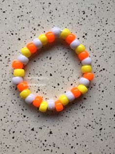 an orange, yellow and white beaded bracelet sitting on top of a gray counter