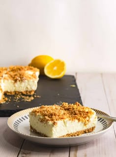 a slice of cheesecake on a plate with a fork and lemons in the background