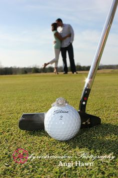 a golf ball sitting on top of a green grass covered field next to a couple