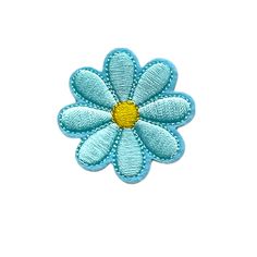 a blue flower with yellow center sitting on top of a white surface, in the shape of a daisy