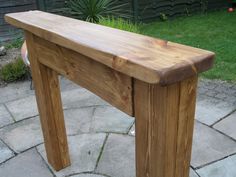 a wooden bench sitting on top of a stone floor next to a grass covered yard