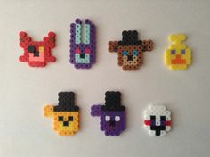 six pixel art magnets are arranged on a white surface, each with different characters