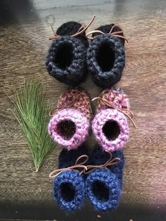 three crocheted baby booties are next to a pine branch