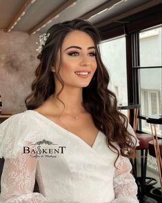 a woman wearing a white wedding dress with long sleeves and a flower in her hair