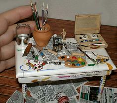 a small table topped with lots of art supplies and paintbrushes on top of it