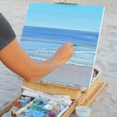 a person painting on an easel at the beach