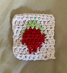 a crocheted square with red and green flowers on it