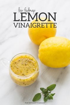 lemon vinaigrette in a small glass jar next to two lemons on a white marble surface