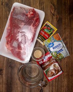 raw meat, seasoning and spices on a cutting board next to a glass bowl